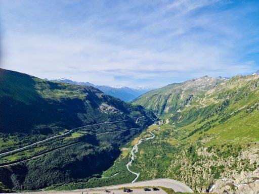 Alpen Berglandschaft mit grünem Tal und einem sich windenden Fluss zwischen den Bergen.